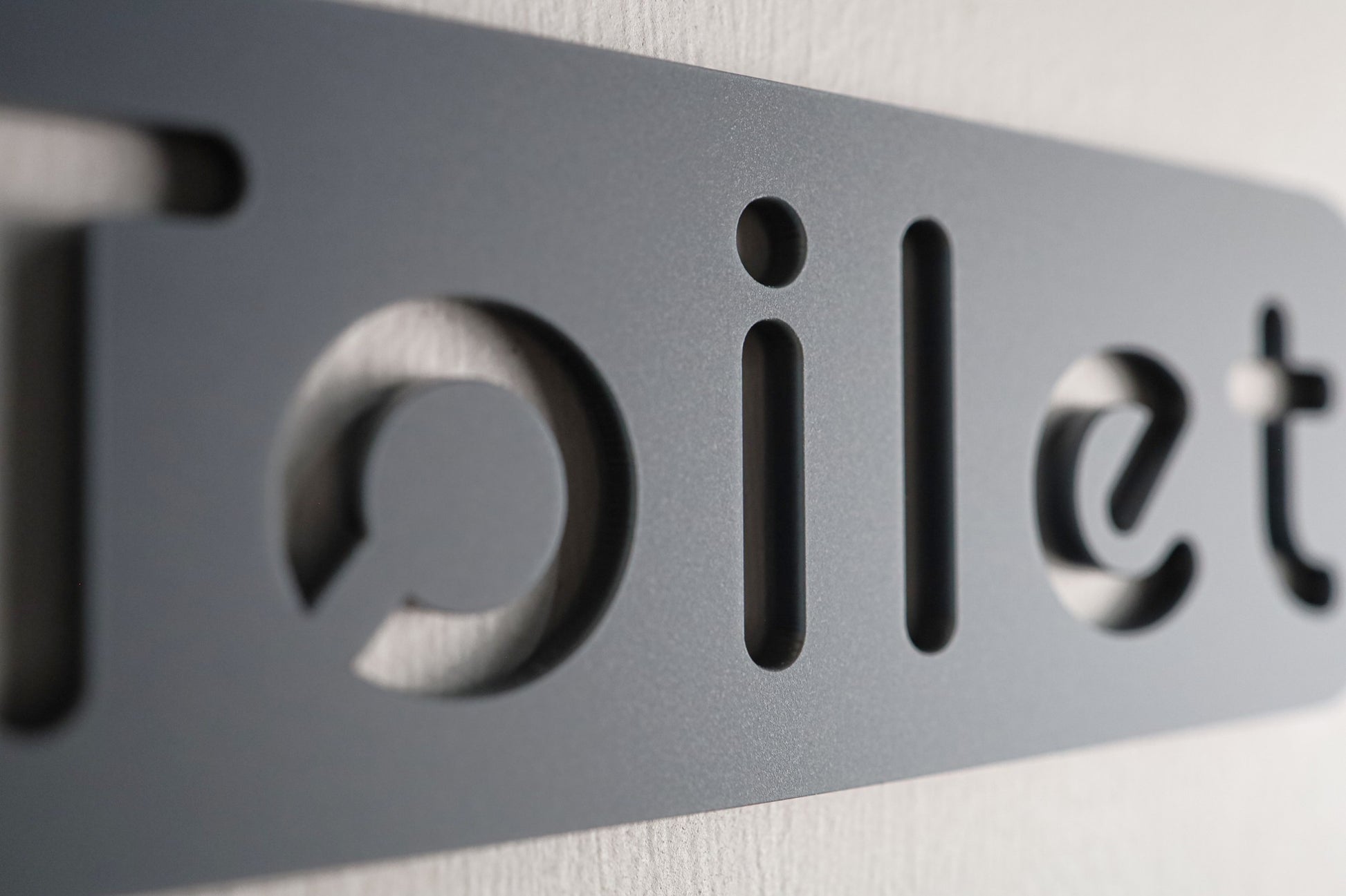 Stylish bathroom sign with a contemporary stone texture and simple, clean lettering.