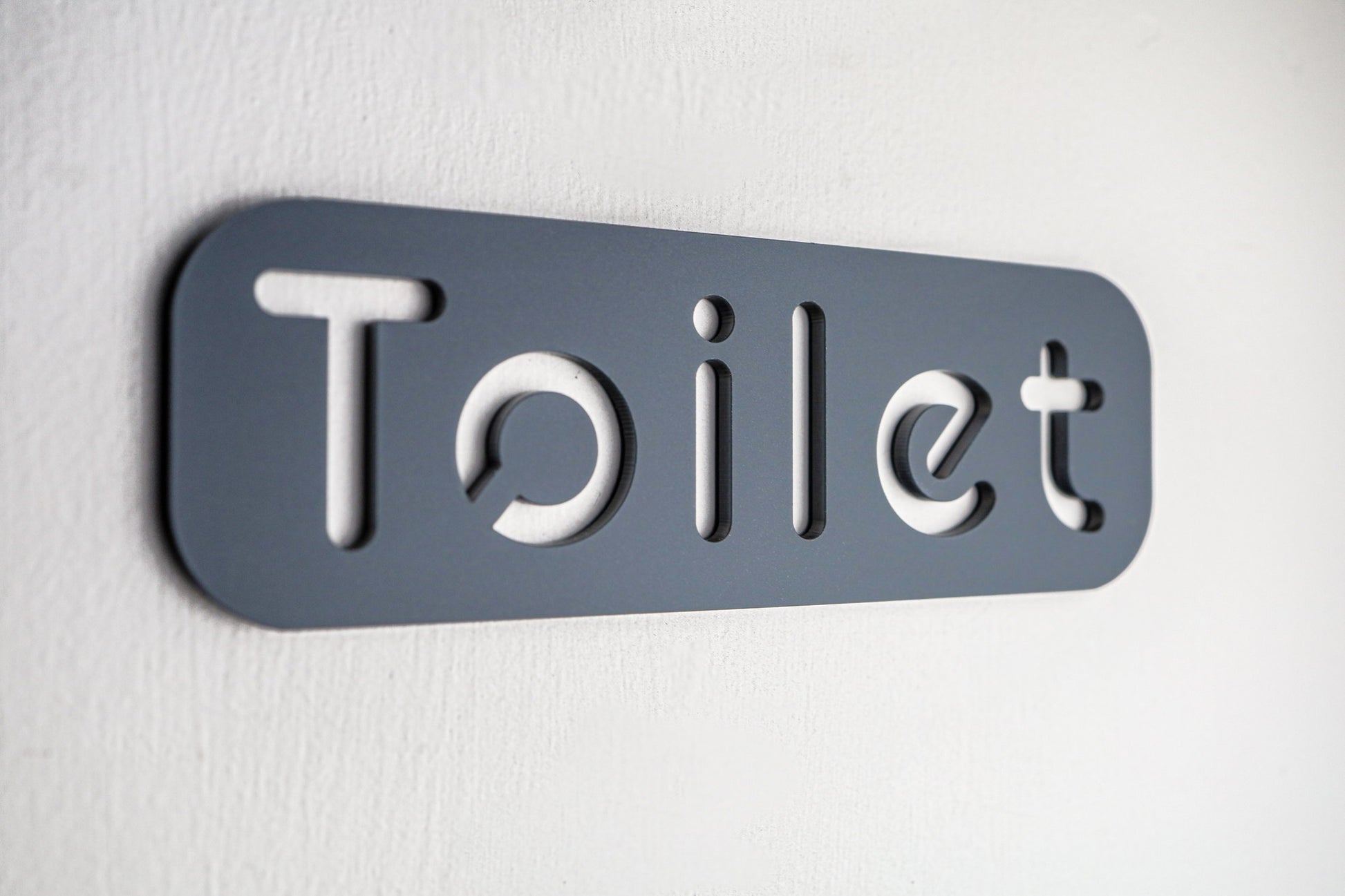 Premium grey acrylic toilet sign with self-adhesive backing for easy installation.