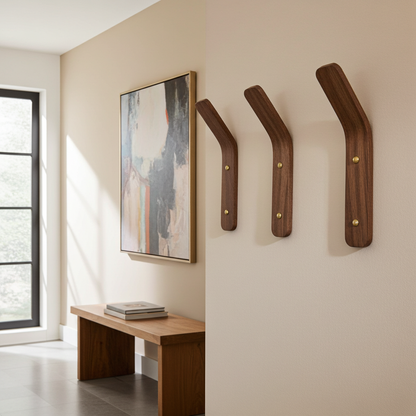 Wooden wall hooks on a beige wall with a bench and abstract painting in the background.