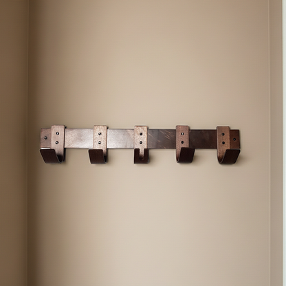 Metal wall hook rack with five hooks on a beige wall.